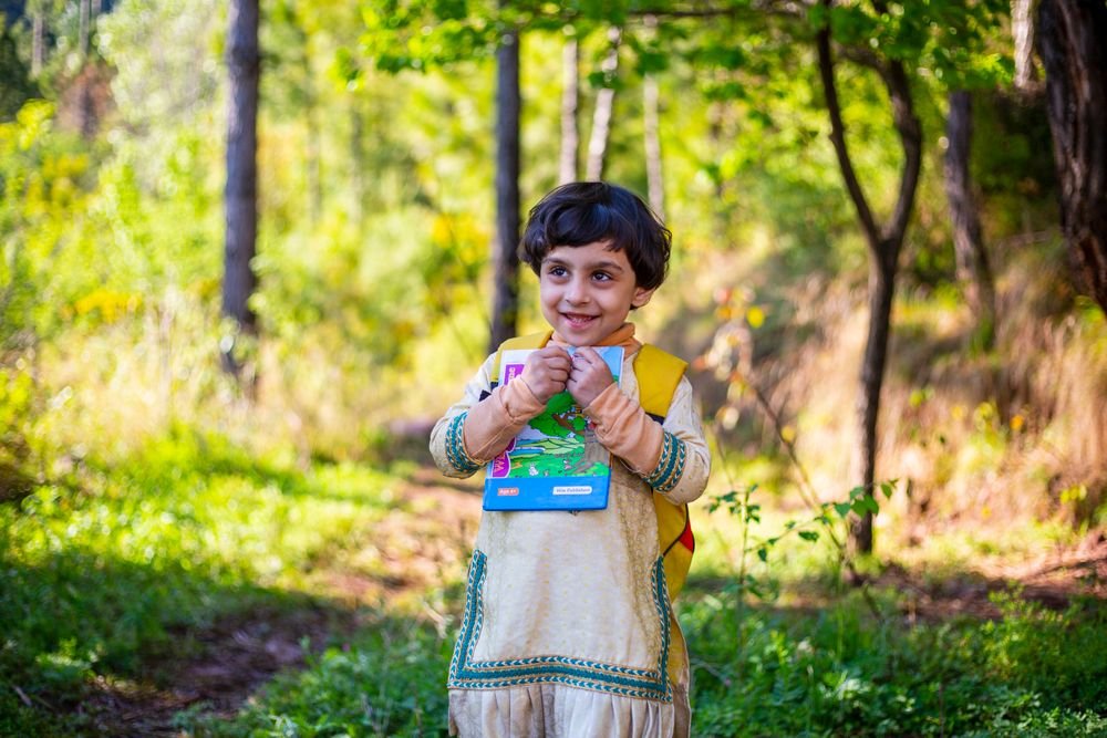 A young girl reading a book outdoors in Pakistan