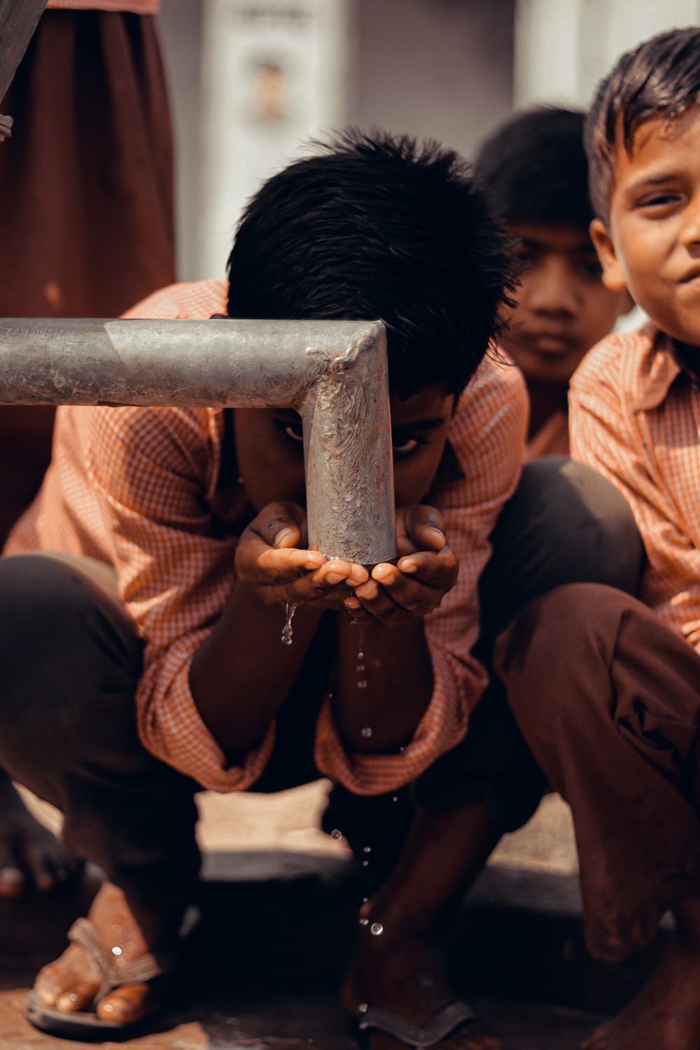 Children drinking from a public water pipe