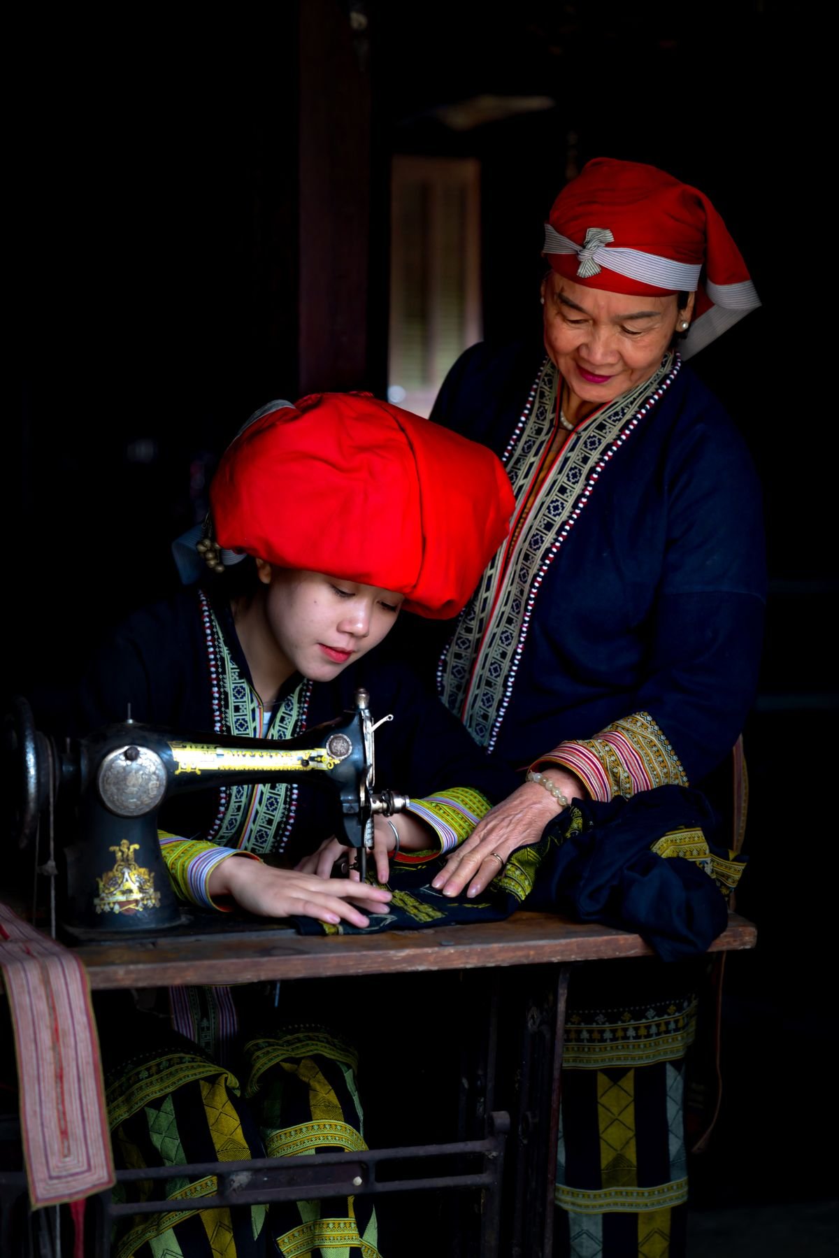 A senior woman teaching a young woman to sew